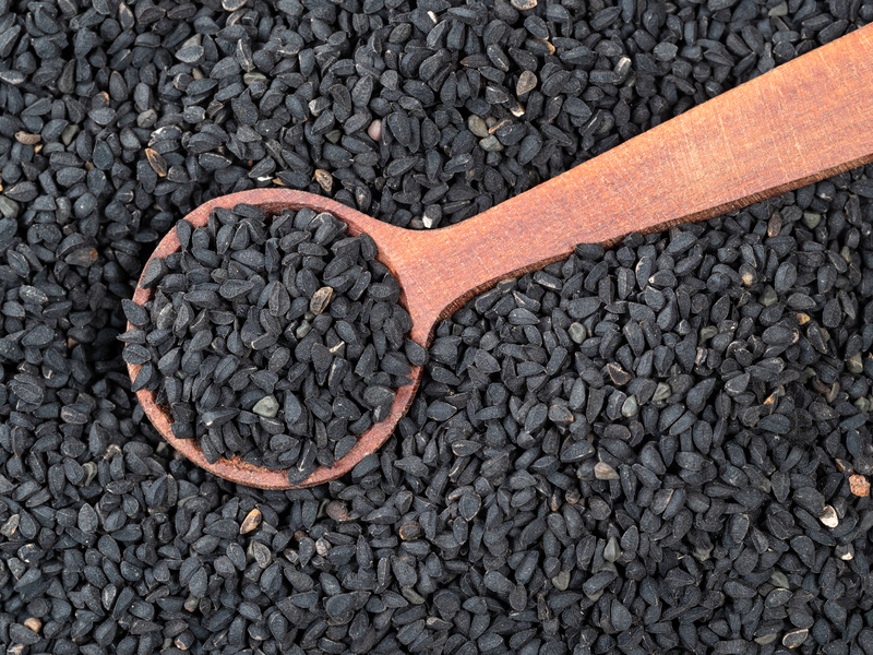 spoon on pile of Nigella sativa seeds closeup